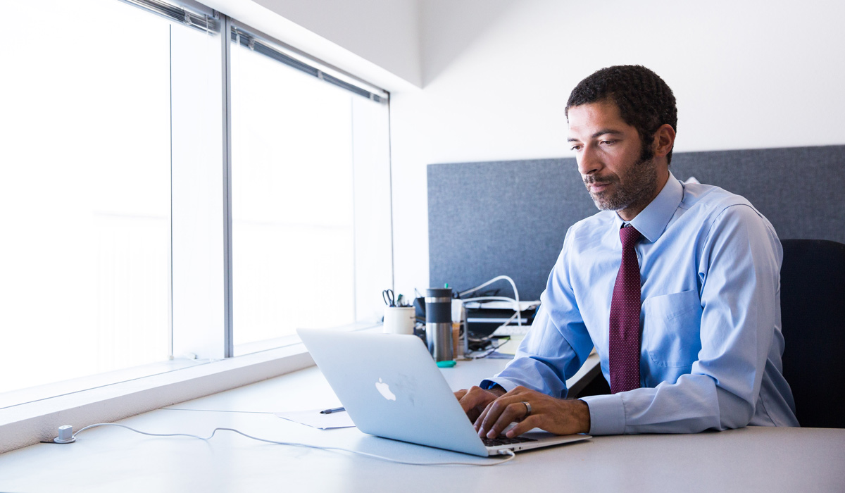 Senior leader sitting in his office reviewing his team's org structure on his laptop. 