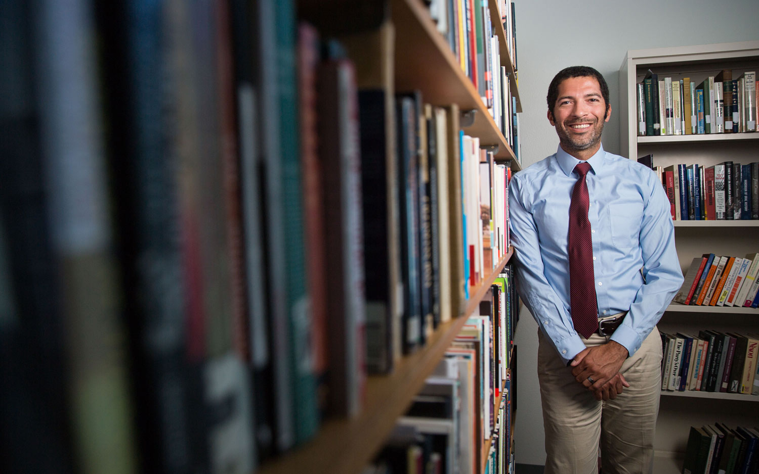 School psychologist standing in front of a bookshelf in the library smiling.