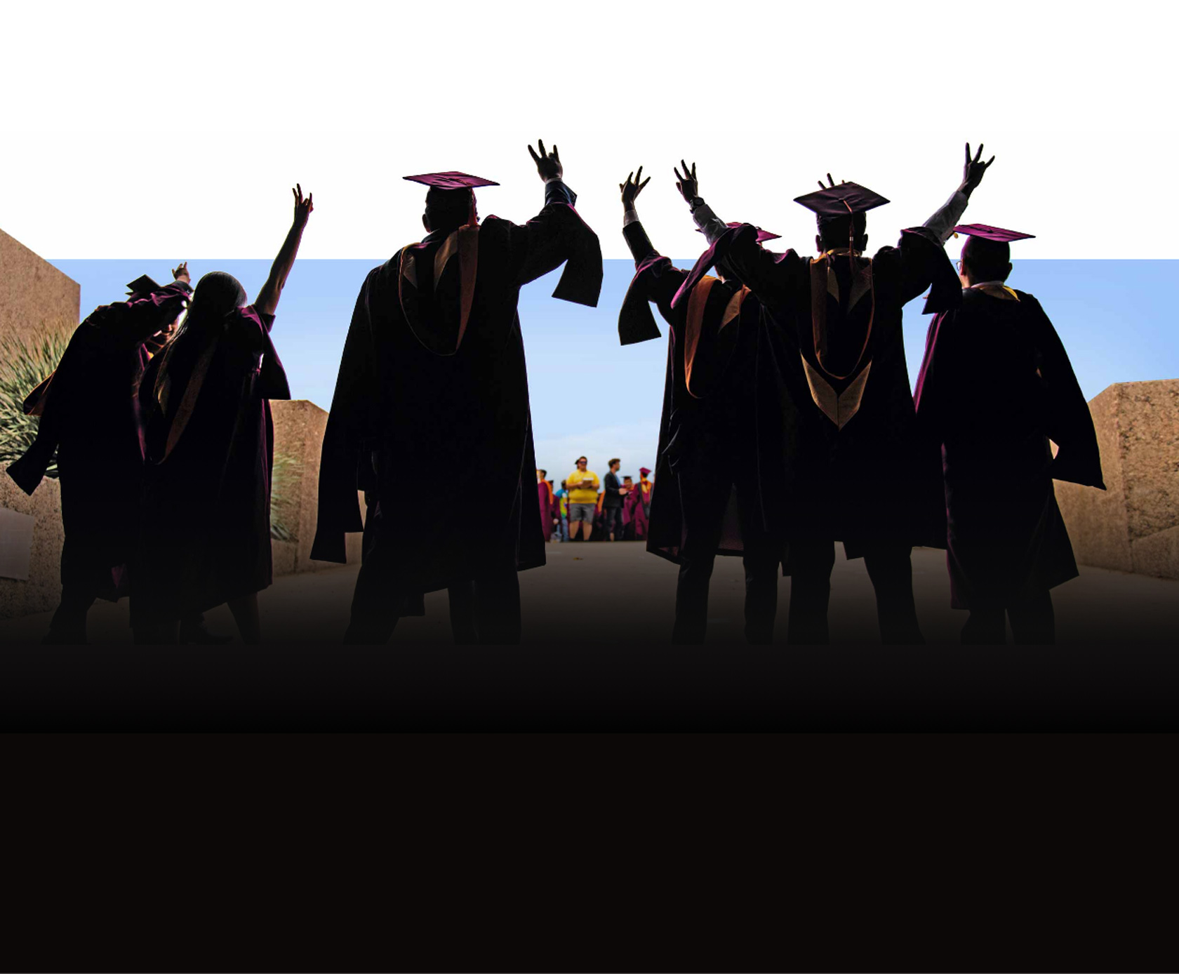 ASU graduates hold up the pitchfork hand sign as they leave a graduation ceremony.