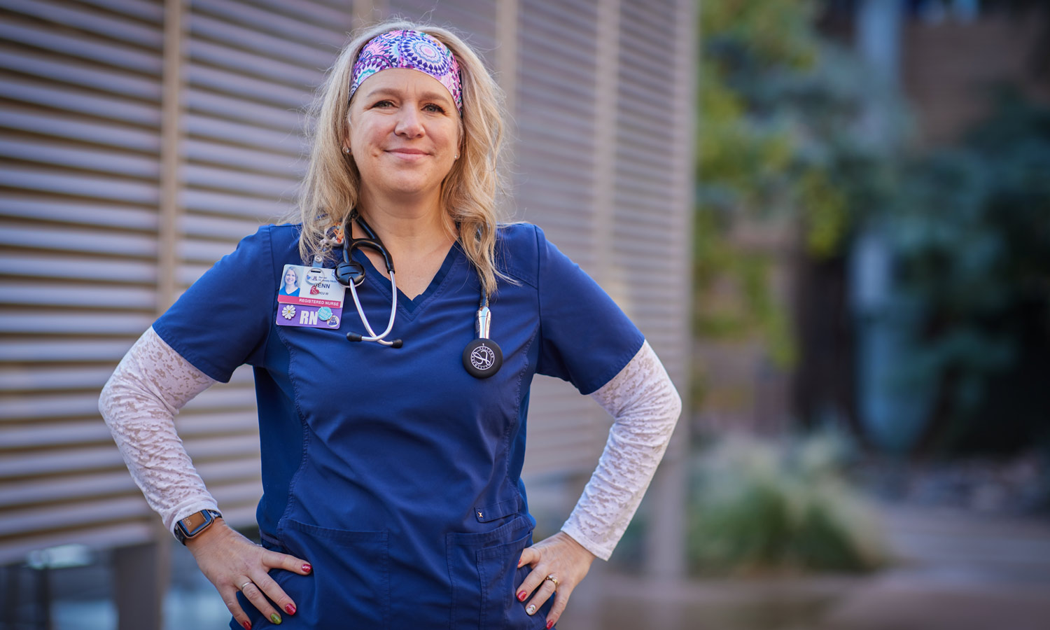 An RN to MSN online student stands outside in scrubs.